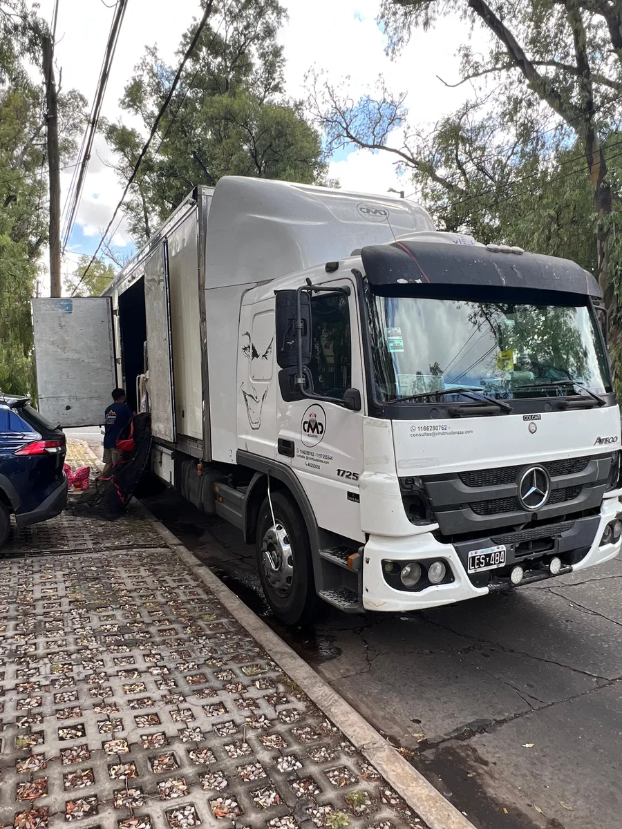 Camión cerrado de Mudandome trabajando en una calle arbolada de Buenos Aires