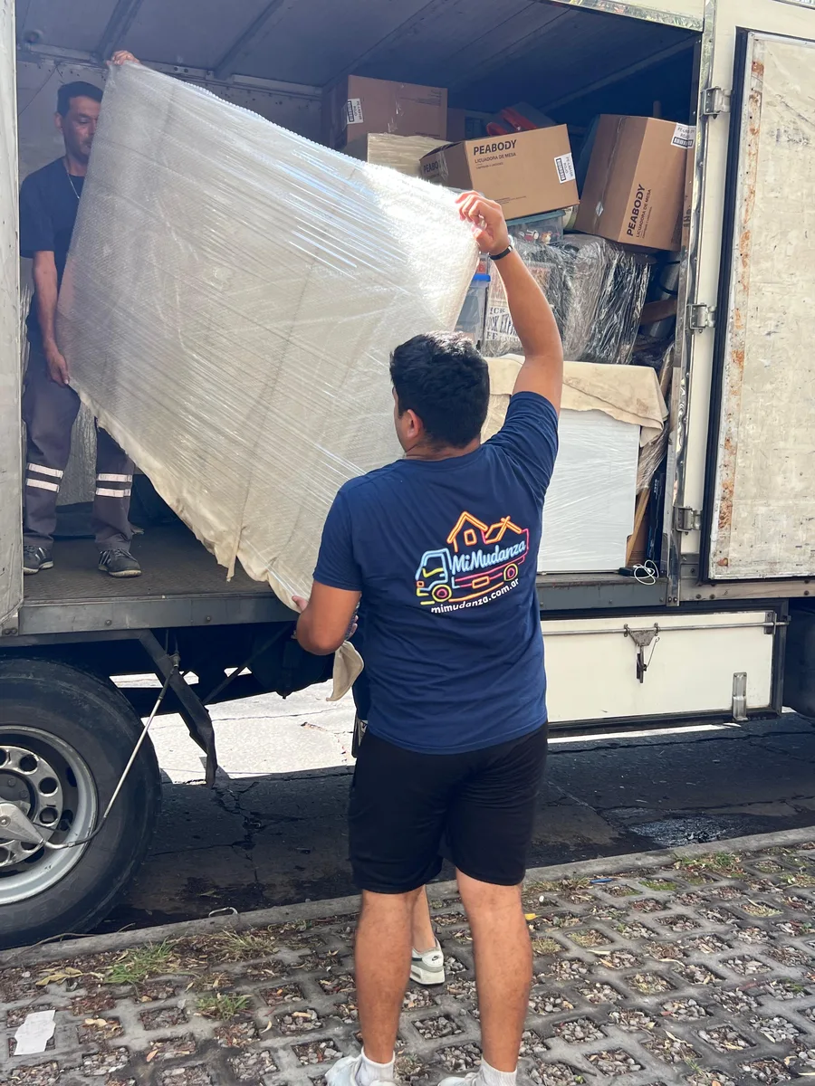 Operario de Mudandome cargando un colchón embalado al camión con cajas rotuladas